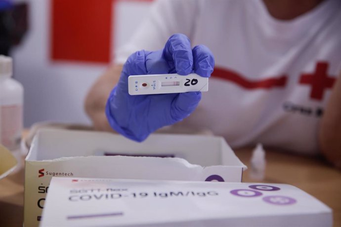 Personal sanitario de Cruz Roja muestra el resultado de un test rápido de detección de anticuerpos IgG e IgM 