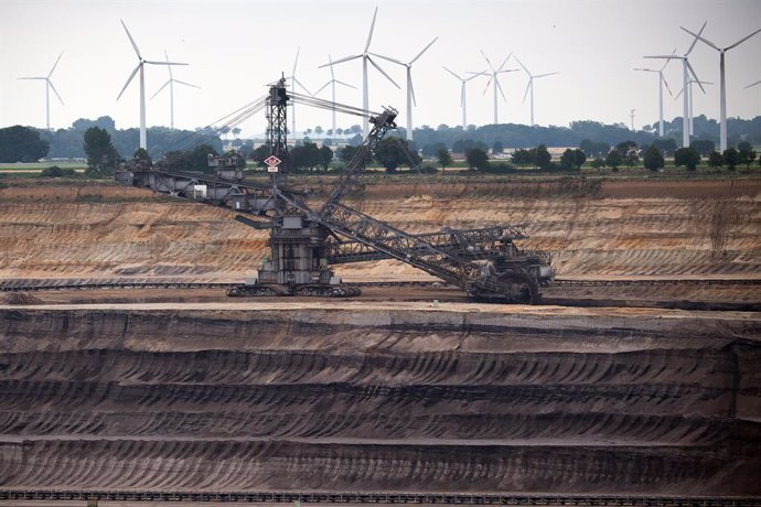03 July 2020, North Rhine-Westphalia, Jackerath: Windmills rotate behind a bucket wheel excavator at the Garzweiler opencast lignite mine to generate electricity. Plans to phase out coal in Germany by 2038, including billions of euros in aid for the reg