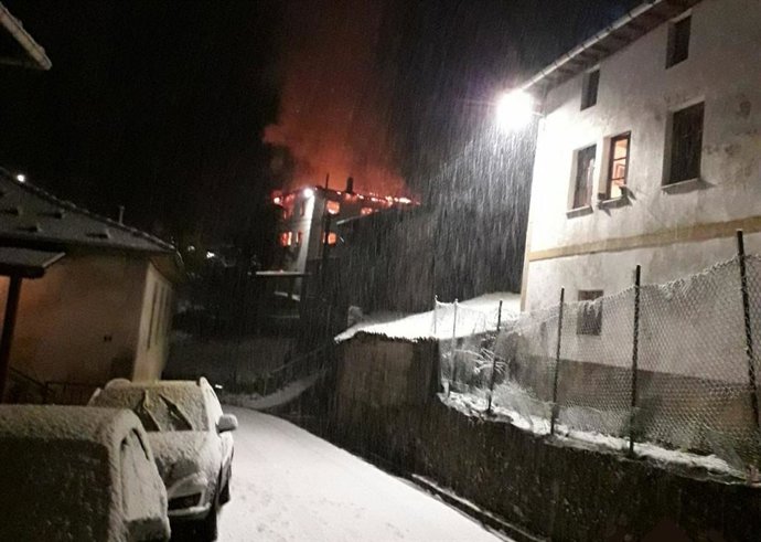 Vivienda incendiada al fondo.