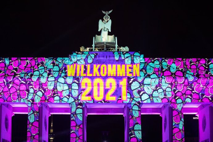 31 December 2020, Berlin: Projectors light up the Brandenburg Gate during the New Year's Eve celebrations. Germany's biggest New Year's Eve party at the Brandenburg Gate was cancelled this year due to coronavirus. Photo: Christoph Soeder/dpa