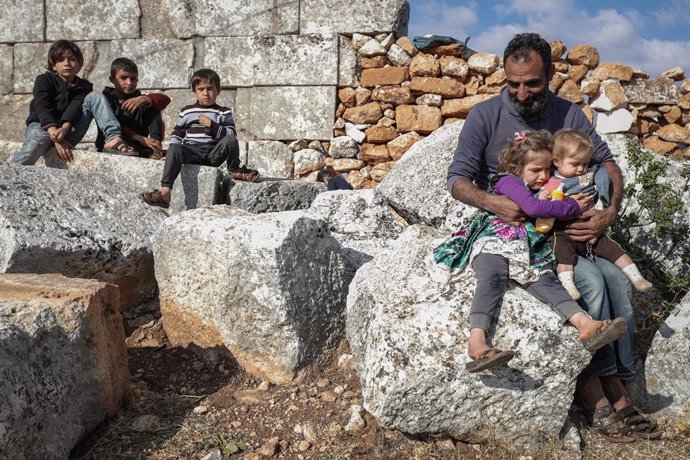 07 November 2020, Syria, Babisqa: Aman sits with his children at the remains of an ancient church in the village of Babisqa. About 6 internally displaced Syrian families, whose homes in the village of Ain La Rose were destroyed by the Syrian government