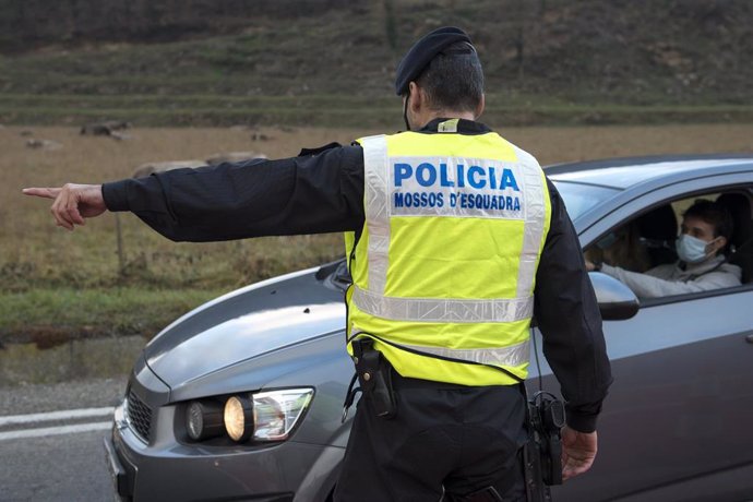 Un Mosso d'Esquadra para a un coche durante el control policial por el confinamiento perimetral en la C-17 a la entrada de Ripoll, en Girona (España), a 24 de diciembre de 2020. Los controles de movilidad se producen debido a que la Generalitat cerró de