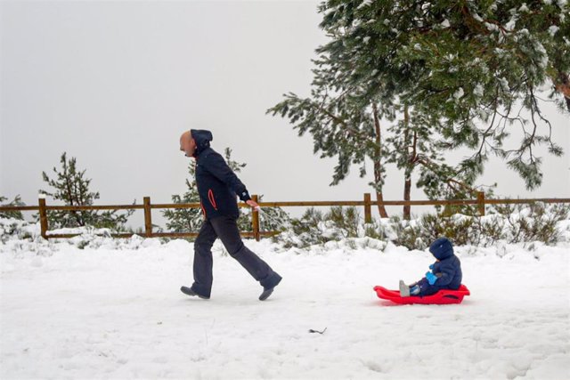 Un padre tira del trineo de su hijo durante el temporal de nieve en la Sierra de Madrid. Archivo.