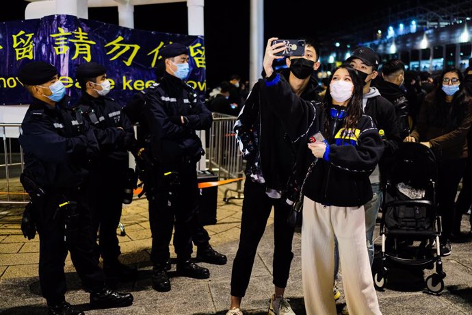 01 January 2021, China, Hong Kong: People take selfies by the Victoria Harbour during New Year's Eve celebrations. As coronavirus (COVID-19) restrictions still in place, annual fireworks were cancelled as well as other events. Photo: Keith Tsuji/ZUMA Wi
