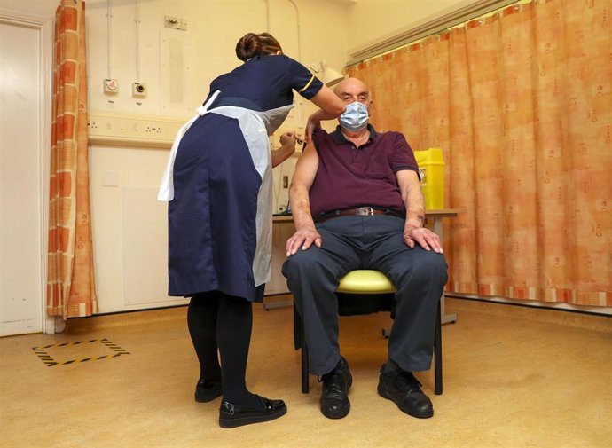 04 January 2021, England, Oxford: Brian Pinker, 82-year-old, receives the AstraZeneca/Oxford coronavirus (COVID-19) vaccine from nurse Sam Foster at the Churchill Hospital, he becomes the first person in the worldto receive this vaccine. National Healt