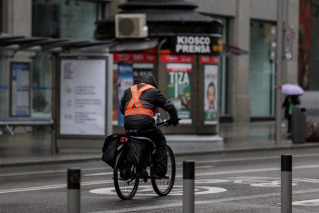 Una persona monta en bicicleta por la Gran Vía madrileña donde las temperaturas han bajado estrepitosamente durante el segundo día de la entrada en vigor de la limitación total de movimientos salvo de los trabajadores de actividades esenciales, medida ado