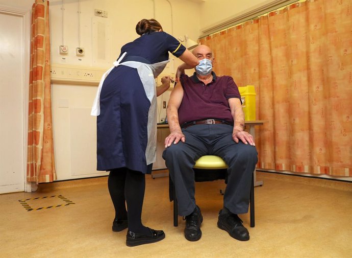 04 January 2021, England, Oxford: Brian Pinker, 82-year-old, receives the AstraZeneca/Oxford coronavirus (COVID-19) vaccine from nurse Sam Foster at the Churchill Hospital, he becomes the first person in the worldto receive this vaccine. National Healt