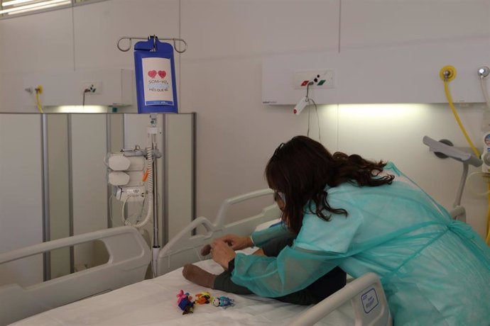 Una profesional sanitaria atiende a un paciente pediátrico con una caja 'Superbox' que reviste con ilustraciones las quimioterapias, sueros, transfusiones y otras medicaciones
