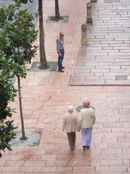 Dos personas mayores pasean por una ciudad.