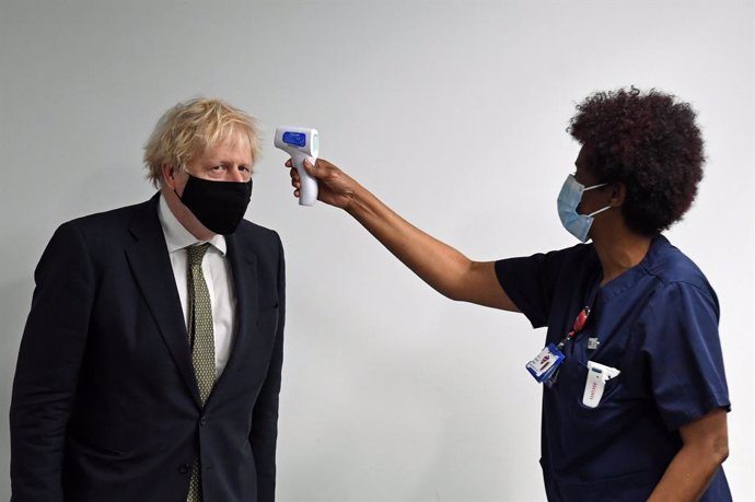 04 January 2021, England, London: A nurse checks the temperature of UK Prime Minister Boris Johnson (L)during a visit to Chase Farm Hospital, on the day that the National Health Service (NHS) ramps up its vaccination programme with 530,000 doses of the
