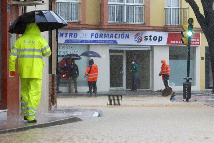 Operarios de los servicios operativos ayudan a retirar el exceso de agua acumulada en la barriada de Campanillas tras el desbordamiento del río  a causa de las fuertes lluvias caída la pasada madrugada. Málaga a 31 de marzo del 2020
