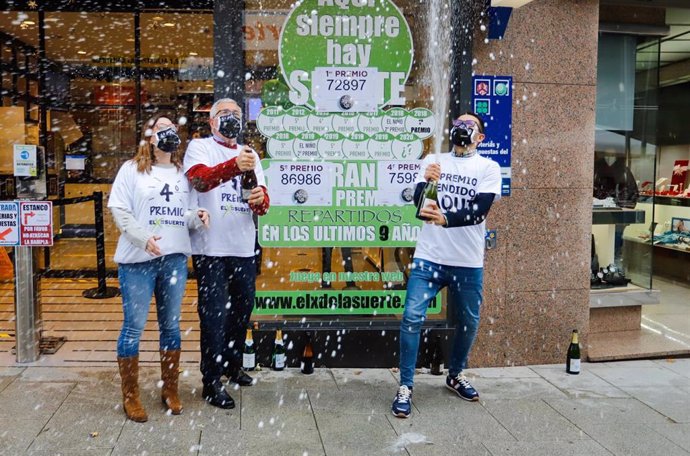 Tres loteros celebran con champán en la administración de lotería situada en la calle Ramón González, 7 en la que se ha repartido parte del número `72.897 correspondiente a 'El Gordo' de la Lotería de Navidad, en O Porriño, Pontevedra/Galicia (España), a