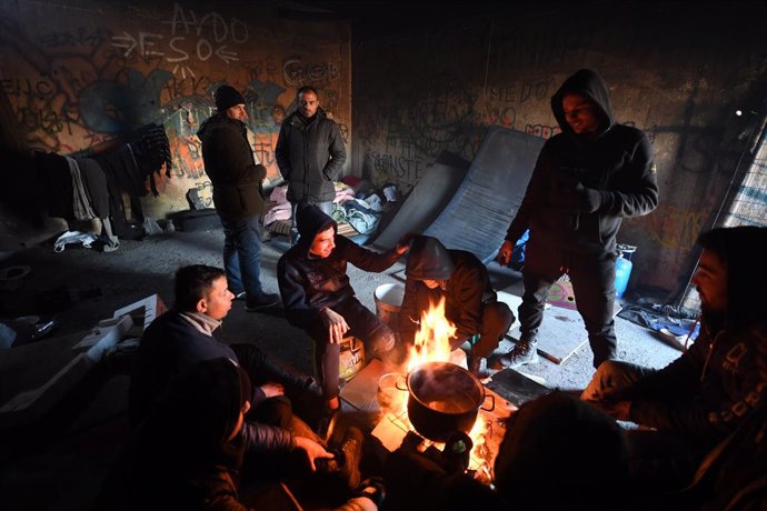 Refugiados egipcios a los pies de un fuego improvisado para protegerse del frío en el campamento de Lipa, en Bihac, ciudad situada en el noroeste de Bosnia y Herzegovina.