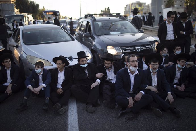 27 December 2020, Israel, Bnei Brak: Ultra-Orthodox Jews block a road during a demonstration staged moments before Israel enters its thirdnationwide lockdown amid the coronavirus pandemic. Photo: Ilia Yefimovich/dpa