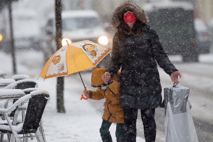 Una madre y su hijo caminan en medio de una gran nevada en Becerrea, en Lugo, Galicia (España), a 4 de diciembre de 2020. Hoy se ha producido la primera gran nevada del otoño en la montaña lucense. La intensa nevada que está cayendo sobre el centro de l