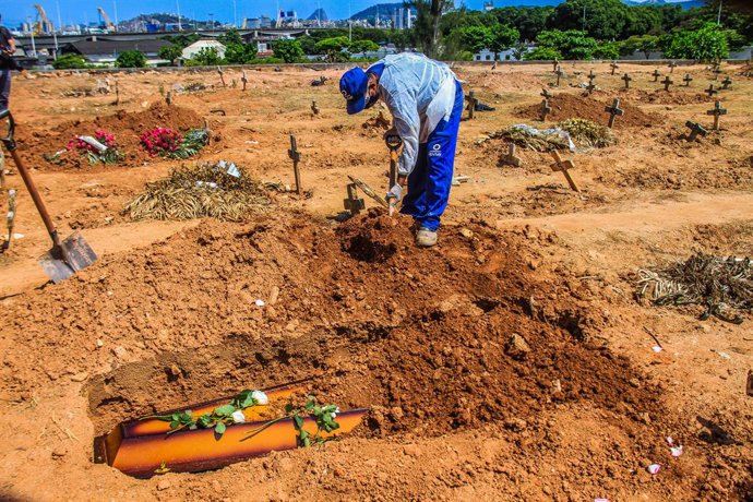16 December 2020, Brazil, Rio de Janeiro: A cemetery worker in protective suits buries the body of a man who died from the coronavirus (COVID-19) at Sao Francisco Xavier cemetery. Photo: Ellan Lustosa/ZUMA Wire/dpa