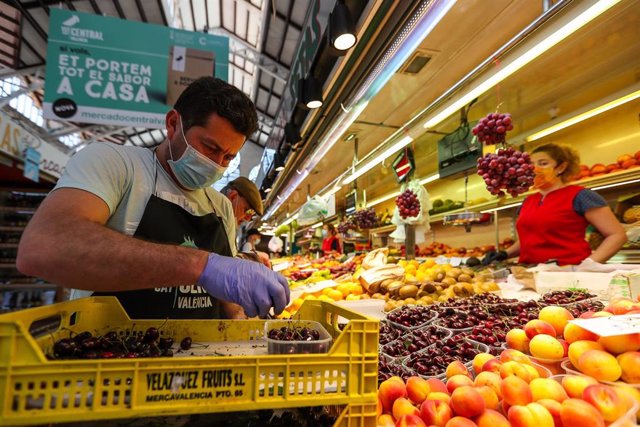 Un hombre trabaja colocando la fruta en una una frutería del Mercado Central de Valencia