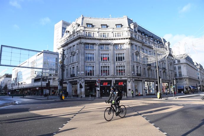 20 December 2020, England, London: A cyclist rides in the almost deserted Oxford Circus shopping street. British Prime Minister Boris Johnson announced a strict lockdown and cancelled Christmas holiday gatherings across London and eastern and south-east