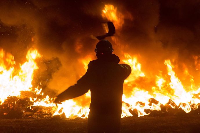Un trabajador tira un elemento a una barricada durante un velatorio nocturno simbólico convocado por la fábrica de Alcoa, en  en San Cibrao, A Mariña, Lugo, Galicia (España), a 28 de noviembre de 2020. 