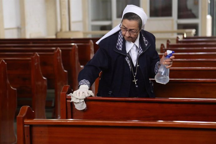 15 March 2020, Colombia, Bogota: A nun disinfects the benches of a church amid the coronavirus (COVID-19) outbreak. Coronavirus has now spread to 17 of the 20 Latin American countries. Photo: Camila Diaz/colprensa/dpa