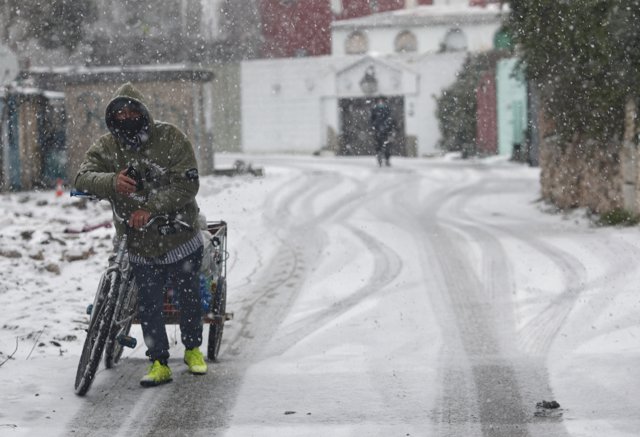 Un hombre con una bicicleta entre la nieve en la Cañada Real, Madrid (España), a 8 de enero de 2021.