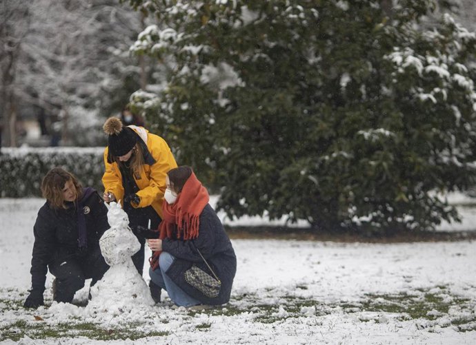 Tres personas juegan con la nieve en el parque del Retiro, tras el paso de la borrasca Filomena, en Madrid (España), a 7 de enero de 2021. 