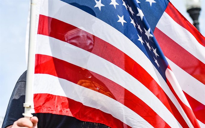 22 August 2020, US, Davenport: A masked man is seen through an American flag during an 'American patriot 2A March' near Modern Woodmen Park. Photo: Meg Mclaughlin/Dispatch Argus via ZUMA Wire/dpa