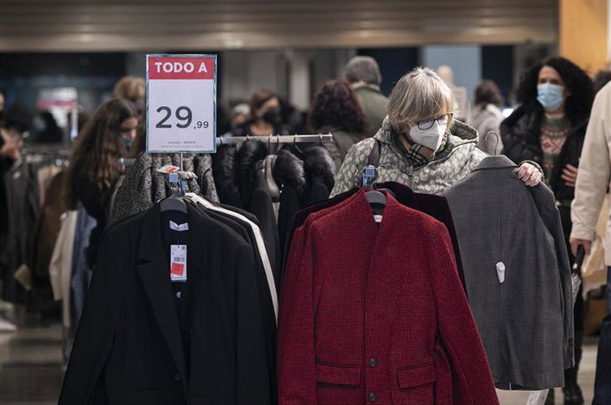 una mujer ojea una prenda en una tienda de ropa durante el comienzo de las rebajas de invierno. 
