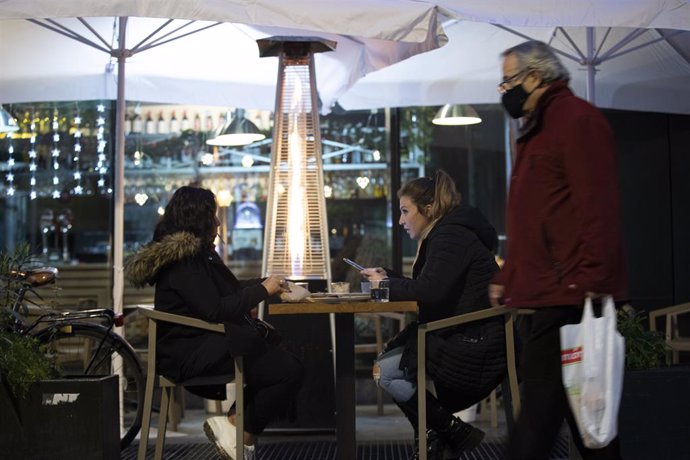 Dos personas en la terraza de un bar, tras la apertura de cafeterías de 18 a 20 horas y de bares y restaurantes de 20 a 22,30 horas con la flexibilización de restricciones de la Junta de Andalucía. En Sevilla (Andalucía, España), a 18 de diciembre de 20