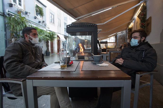 Dos jovenes toman una consumicion en una terraza en Lugo