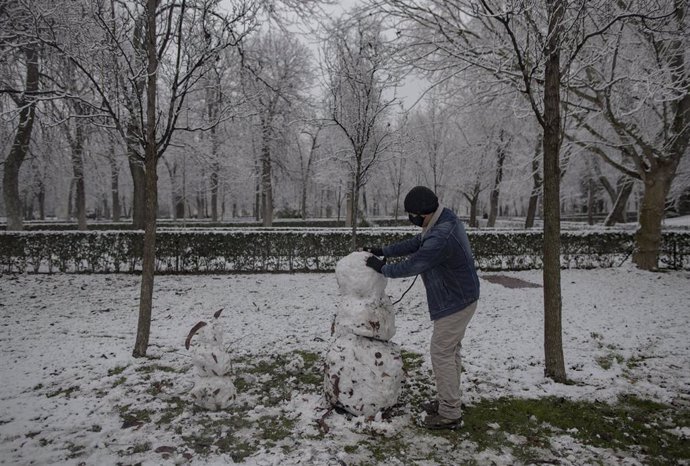 Un hombre junto a un muñeco de nieve