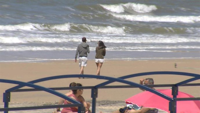 Imagen de la playa de Matalascañas (Huelva) con personas paseando con ropa de abrigo.