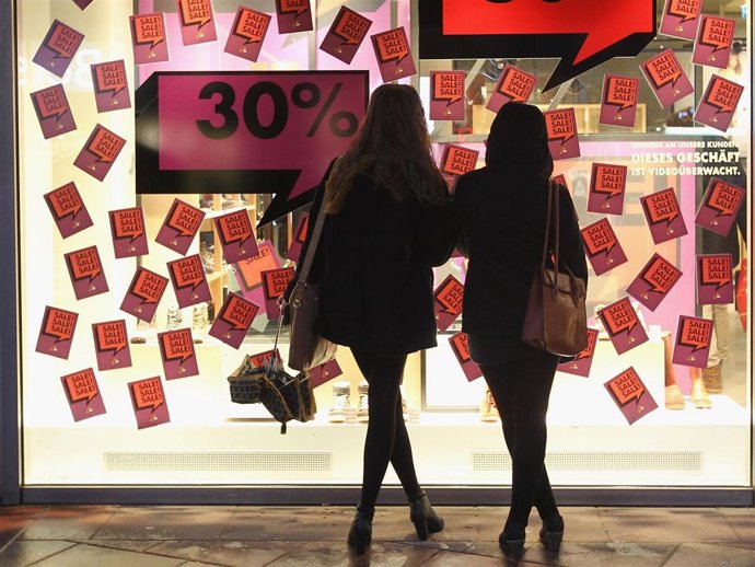 Two young women look at the display window of a shoe store advertising big sales on December 13, 2011 in Berlin, Germany.