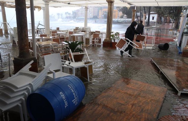 Varias personas intentan recogen el mobiliario de una terraza ante las inundaciones por la borrasca Filomena en Málaga