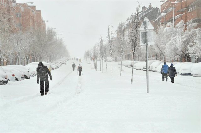 Algunas personas caminan por una calzada completamente cubierta de nieve de una calle en Alcobendas, Madrid (España) a 9 de enero de 2021.La borrasca Filomena golpea con fuerza Madrid, donde se han cerrado al tráfico circunvalaciones y túneles. Las acumul