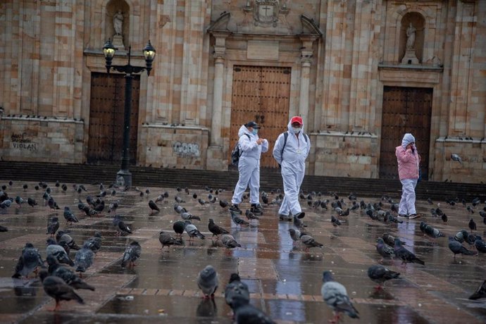 Un grupo de personas camina por una vacía plaza de Bolívar en Bogotá en el segundo día de cuarentena estricta.