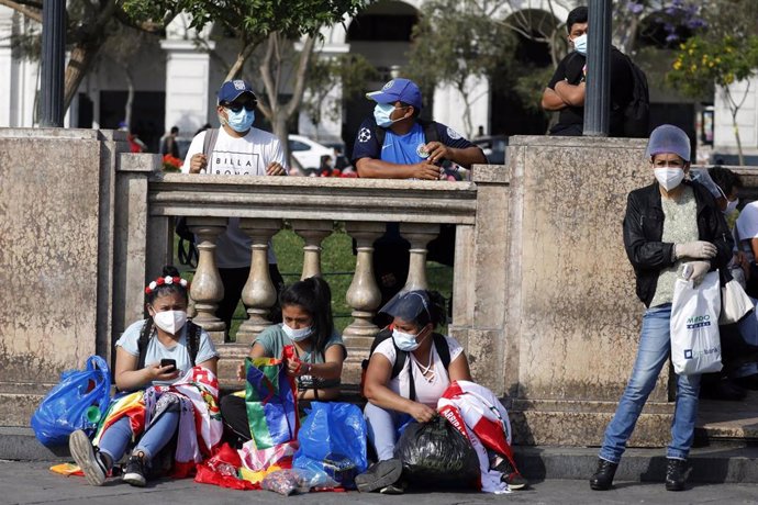 Varias personas sentadas en la calle en Lima. 