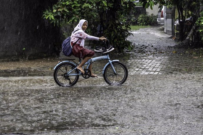 Una chica monta en bici durante una tormenta en Indonesia