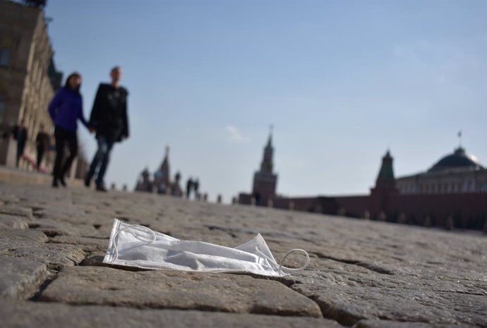 28 March 2020, Russia, Moscow: A couple walks in the sunshine across the Red Square past a discarded face mask. In the Russian capital, stricter regulations to combat the coronavirus (COVID-19) pandemic. Photo: Christian Thiele/dpa