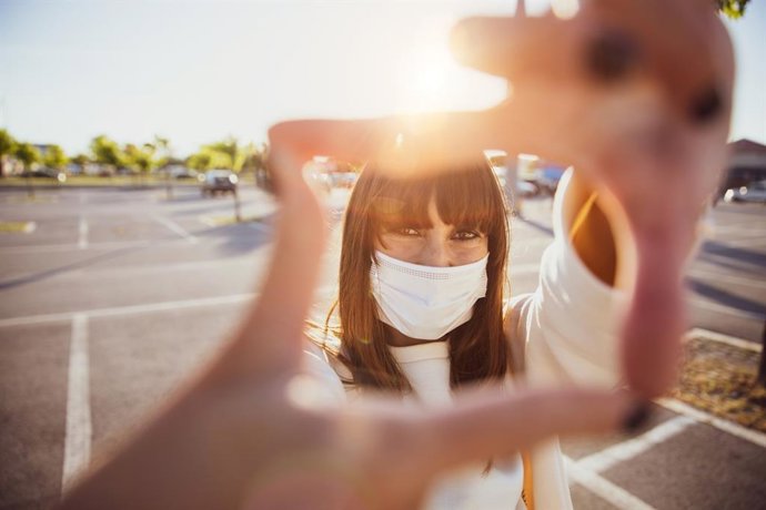 Mujer sonriendo con mascarilla higiénica.