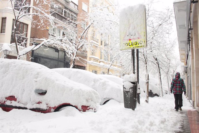 Una persona passeja per un cntric carrer cobert de neu al costat de l'accés d'una escola a Madrid (Espanya) 9 de gener del 2021.