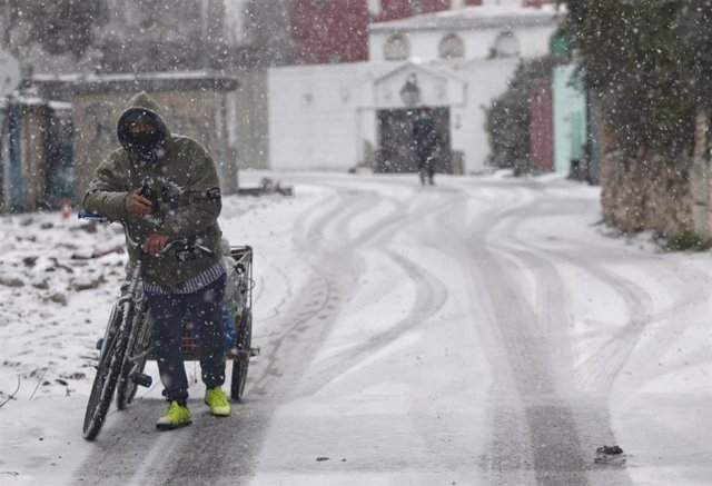 Un hombre con una bicicleta entre la nieve en la Cañada Real Galiana.