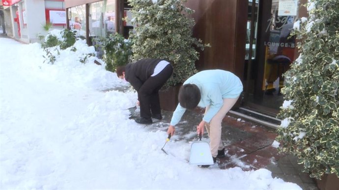 Vecinos y hosteleros limpian las calles llenas de nieve.