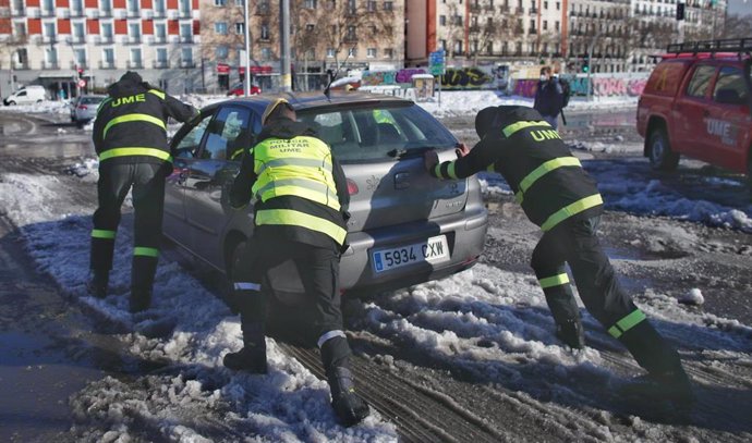 Militares de la UME ayudan a un coche a salir de la nieve en la Estación Puerta de Atocha, en Madrid (España). 9