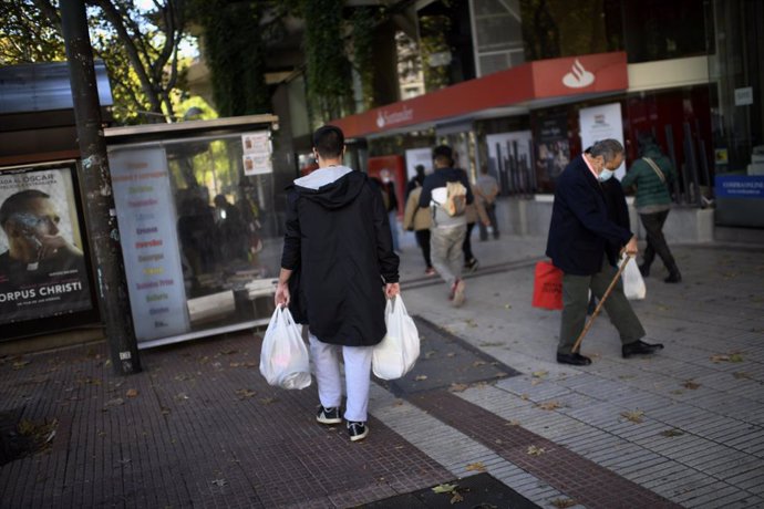 Un hombre lleva varias bolsas de supermercado en la zona básica de salud de Guzmán el Bueno, en el distrito de Chamberí, en Madrid (España), a 26 de octubre de 2020. Guzmán el Bueno es una de las zonas básicas de salud ZBS- en las que, desde hoy, entra