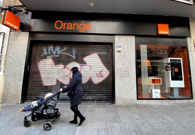 Una mujer pasea frente a una tienda de de la compañía telefónica Orange.