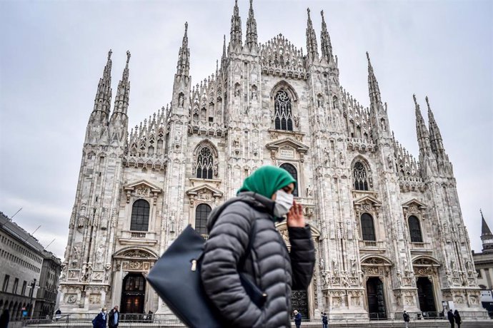 Una mujer con mascarilla pasa frente a la Catedral de Milán