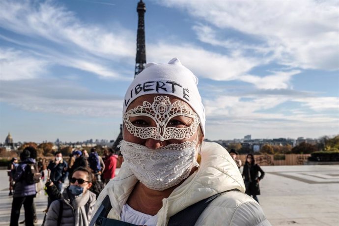 Una simpatizante del movimiento de los 'chalecos amarillos' con mascarilla junto a la Torre Eiffel de París