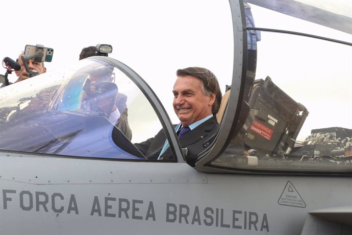 HANDOUT - 23 October 2020, Brazil, Brasilia: Brazilian President Jair Bolsonaro (R) sits inside the cockpit of a Swedish-made Saab JAS 39 Gripen jet fighter during a ceremony held on the Brazilian Aviator's Day. The aircraft is one of 36 Gripen jets bou