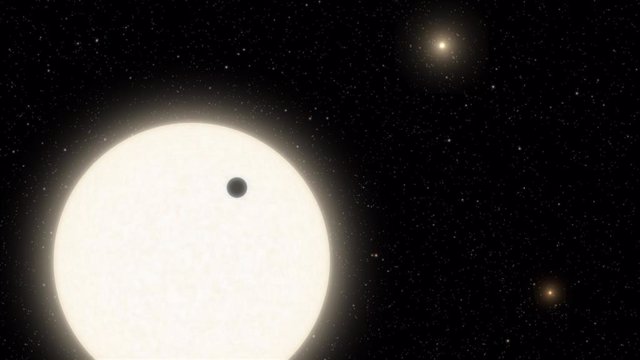 Esta ilustración muestra el planeta KOI-5Ab en tránsito por la cara de una estrella similar al Sol, que es parte de un sistema de estrellas triples ubicado a 1.800 años luz de distancia en la constelación de Cygnus